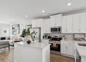 Thumbnail 1 of 19 - A modern kitchen with white cabinets and stainless steel appliances.