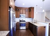 Thumbnail 15 of 26 - Contemporary Kitchen with Dark Wood Cabinetry, Marble Countertops, and Sleek Appliances at Moenave Townhomes in Springdale, Utah