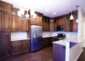 Thumbnail 16 of 26 - Spacious Kitchen with Dark Wood Cabinetry, Wood Flooring, Light Fixtures, and Marble Countertops at Moenave Townhomes in Springdale, Utah