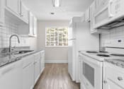 Thumbnail 6 of 22 - A kitchen with white cabinets and a marble countertop.