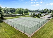 Thumbnail 18 of 22 - A tennis court surrounded by a fence with a clear blue sky above.