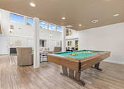 Thumbnail 16 of 22 - A pool table is in the middle of a room with a light colored floor and walls.