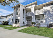 Thumbnail 1 of 19 - Apartment building with a white facade and a green lawn in front.