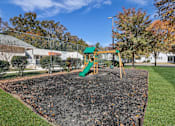 Thumbnail 7 of 19 - A playground with a green slide and a sandbox.