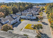 Thumbnail 3 of 19 - A parking lot is in front of a white building with a yellow arrow pointing to the right.