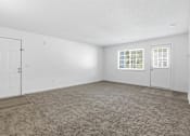 Thumbnail 10 of 19 - A room with a carpeted floor, a window with blinds, and a door.