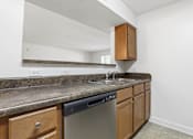 Thumbnail 16 of 19 - A kitchen with a granite countertop and wooden cabinets.