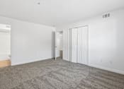 Thumbnail 13 of 19 - A large, empty room with carpeted flooring and white walls.