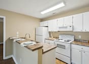 Thumbnail 9 of 14 - A kitchen with white appliances and a granite counter.