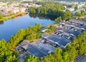 Thumbnail 3 of 14 - A parking lot is surrounded by trees and a body of water.