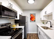 Thumbnail 14 of 15 - an apartment kitchen with white cabinets and stainless steel appliances