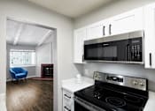 Thumbnail 13 of 15 - a kitchen with a stove and a microwave and a living room