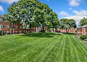 Thumbnail 25 of 51 - A large grassy area in front of a building with trees.