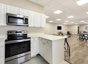 Thumbnail 16 of 22 - A kitchen with white cabinets and a black stove top oven.
