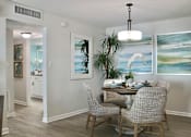 Thumbnail 4 of 23 - A dining room with a table set for two and a painting on the wall.