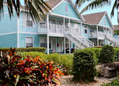 Thumbnail 16 of 23 - A blue house with a white balcony and stairs leading to the front door.