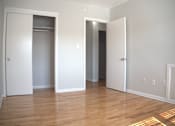 Thumbnail 45 of 51 - an empty living room with a wood floor and three closet doors