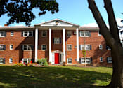 Thumbnail 40 of 51 - a large brick building with a red door and a tree