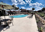 Thumbnail 13 of 56 - A pool area with chairs and umbrellas.