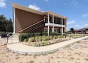 Thumbnail 5 of 56 - A modern building with a brown facade and a staircase leading to the entrance.