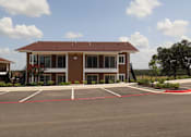 Thumbnail 11 of 56 - A building with a parking lot in front of it.
