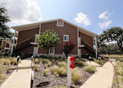 Thumbnail 4 of 56 - A red fire hydrant is in front of a building with a brown and beige exterior.