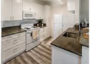 Thumbnail 42 of 56 - A kitchen with white cabinets and a black countertop.