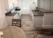 Thumbnail 28 of 56 - A kitchen with white cabinets and black countertops.