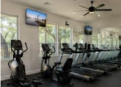 Thumbnail 55 of 56 - A gym with treadmills and elliptical machines.