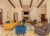 Thumbnail 41 of 43 - A living room with a yellow couch, blue chair, and a fireplace at The Villages at Lost Creek Apartments, San Antonio