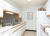 Thumbnail 1 of 11 - A kitchen with white cabinets and a fridge.