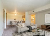 Thumbnail 8 of 11 - A living room with a grey couch and a coffee table.