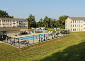 Thumbnail 11 of 11 - A large grassy area with a pool and a building in the background.