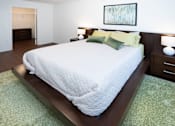 Thumbnail 7 of 13 - A bed with a white comforter and green pillows is in a room with a painting on the wall.