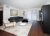 Thumbnail 1 of 13 - A black couch sits in a living room with a wooden chair and coffee table.