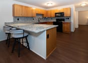 Thumbnail 4 of 13 - A kitchen with a granite countertop and wooden cabinets.