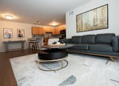 Thumbnail 2 of 13 - A black leather sofa sits in a living room with a coffee table in front of it.