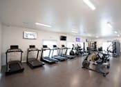 Thumbnail 12 of 13 - A gym with treadmills, elliptical machines, and other exercise equipment.