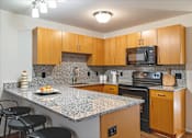 Thumbnail 1 of 8 - A kitchen with wooden cabinets and granite countertops.