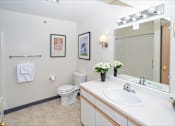 Thumbnail 9 of 13 - A white toilet sits in a bathroom next to a sink and a mirror.