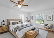 Thumbnail 7 of 17 - A bedroom with a bed, nightstand, chair, and a ceiling fan.
