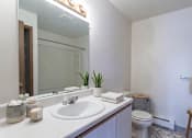 Thumbnail 7 of 10 - A white bathroom with a sink, toilet, and mirror.