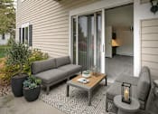 Thumbnail 8 of 10 - A grey couch sits on a patio with a table and a candle.