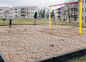 Thumbnail 27 of 33 - A playground with a red swing set and a blue slide.
