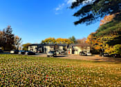 Thumbnail 2 of 15 - a house in the middle of a grassy field with cars parked in front of it