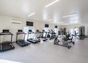 Thumbnail 14 of 17 - A gym with treadmills and elliptical machines.