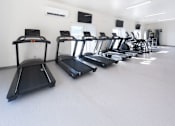 Thumbnail 13 of 17 - A row of treadmills are lined up in a gym.