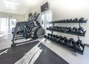 Thumbnail 15 of 17 - A gym with a row of dumbbells on a rack and a treadmill.