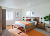 Thumbnail 4 of 15 - A bedroom with a bed, nightstand, and a plant.