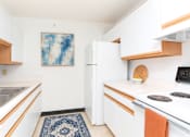 Thumbnail 3 of 15 - A kitchen with white cabinets and a blue rug on the floor.